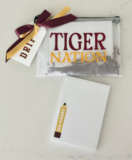 Clear pouch with 'Tiger Nation' text, pencil-shaped notepad, and decorative ribbon on a light gray background
